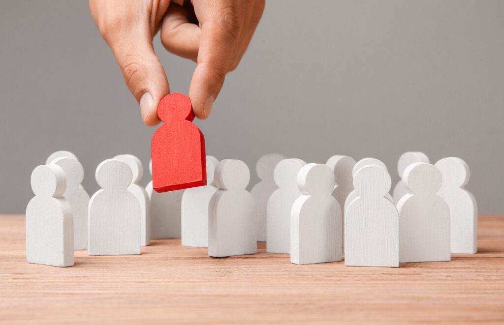 A small wooden person being put with others, indicating employment opportunities and real estate investment