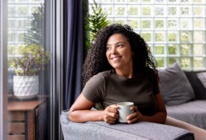 Woman relaxing at home drinking a cup of coffee and smiling.