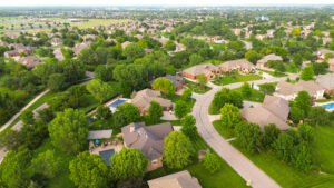 Aerial view of a Wichita, KS, neighborhood featuring houses, trees, and winding streets under a clear blue sky.
