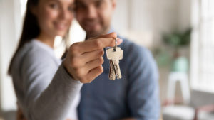 Happy Couple with Woman Holding Keys