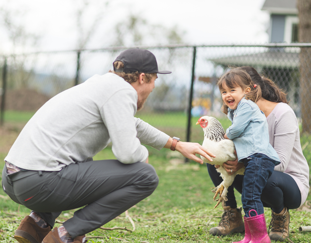 Happy Family Playing with a Chicken in the Yard of their Arlington Rental Home