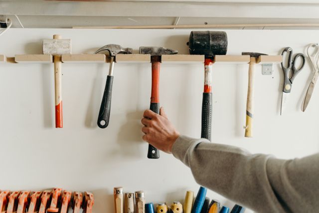 a person reaching for a tool hanging on a wall