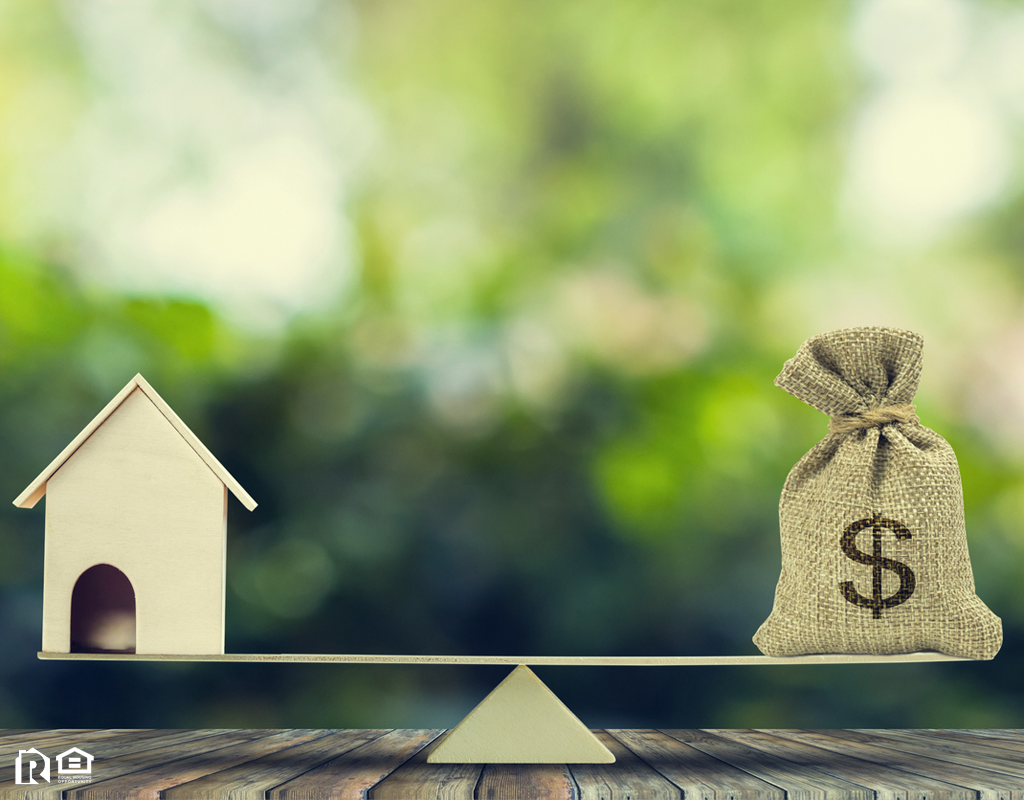 A Model House on a Scale with Money Bag on the Opposite Side