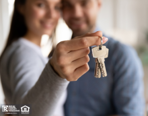 Happy Couple with Woman Holding Keys