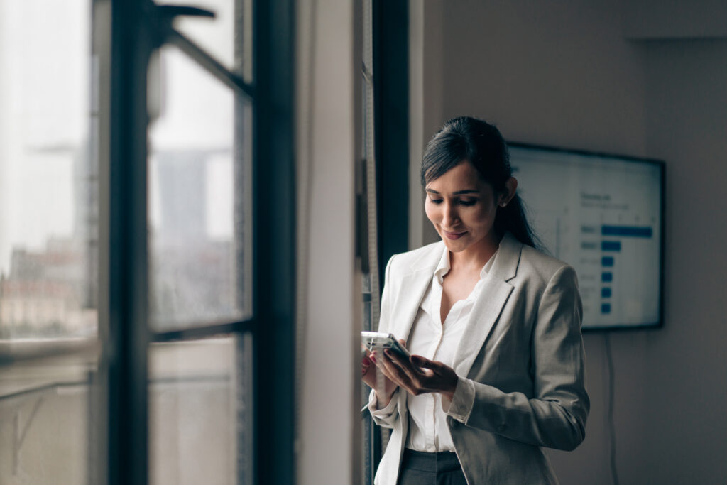 Real estate investor using a phone in the office to research the market. 