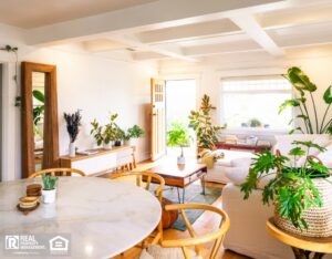 A cozy living room featuring a wooden table surrounded by four chairs, with soft lighting and decorative elements.