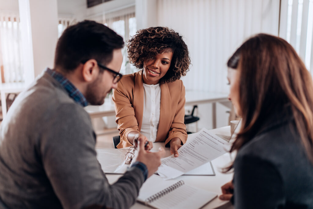 Three people gathered around a table to discuss and finalize a lease agreement.