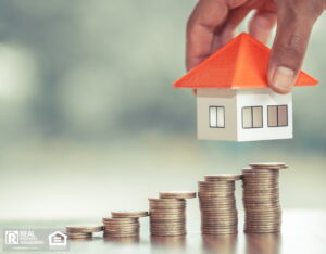 Image of a house over stacks of coins, symbolizing the upward trend in the housing market.