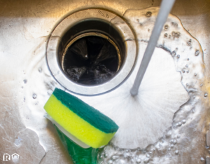 Water Running into a Sink with a Pot Scrubber Lying In It