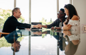 Property manager shaking hands with new tenants while sitting across a table