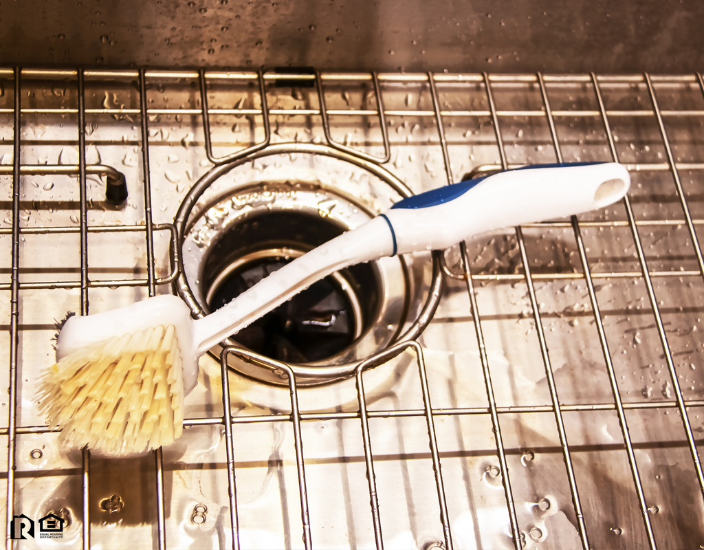 Sink with a Garbage Disposal and a Wire Rack with a Scrub Brush Laying On It