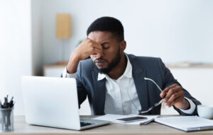 Real estate investor at his laptop appearing stressed over avoidable investment errors 