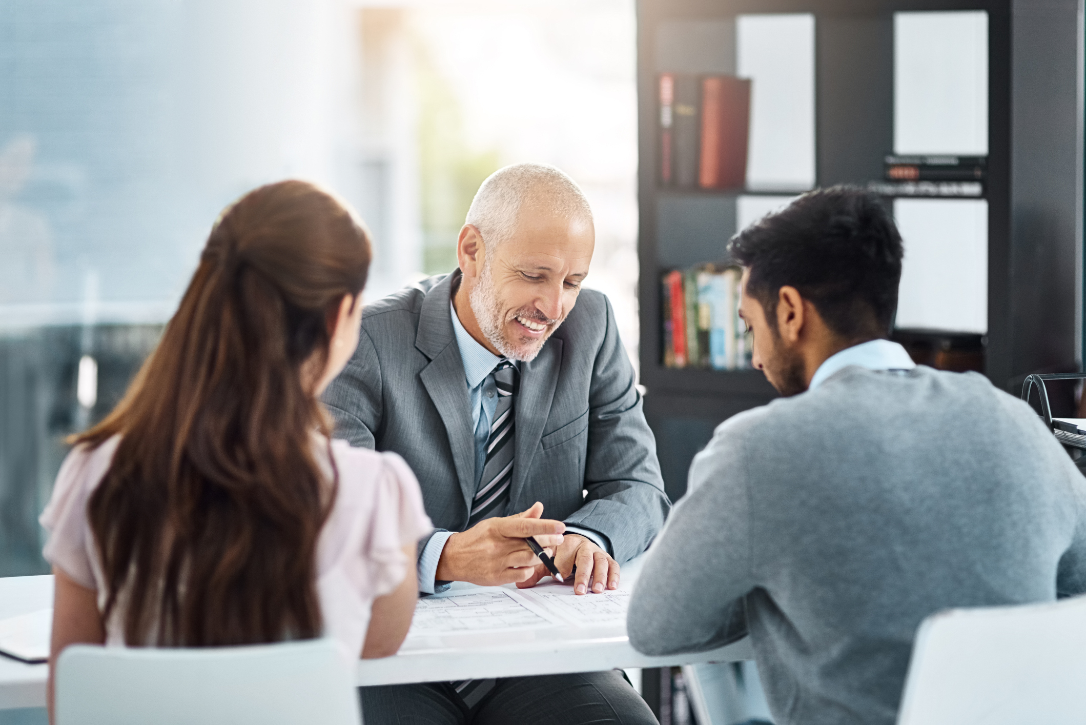 Three people in business attire engaged in conversation.