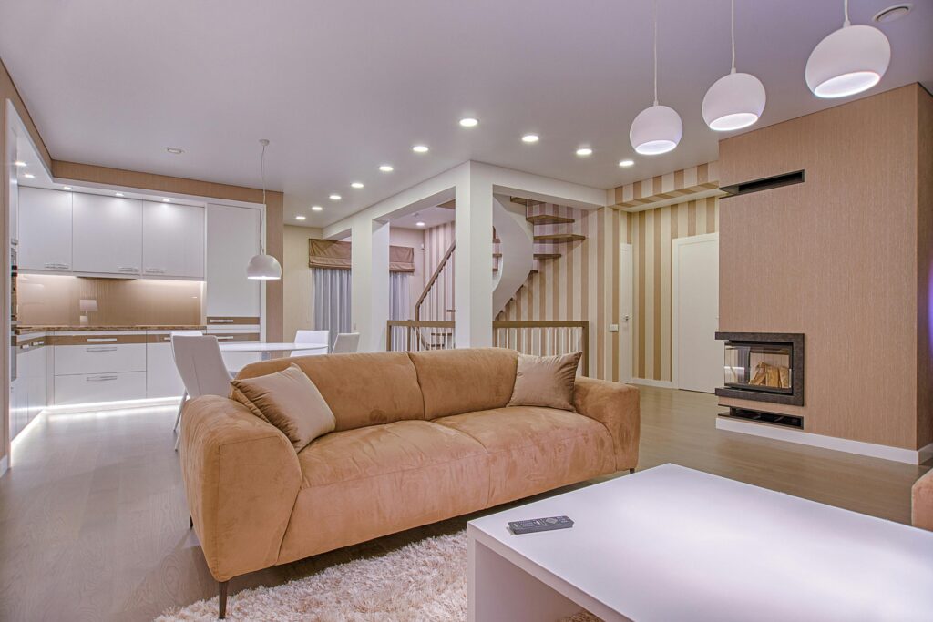 earth tone living room with tan couch and spiral staircase in the back