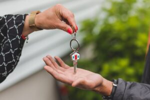 person handing over house keys to someone else