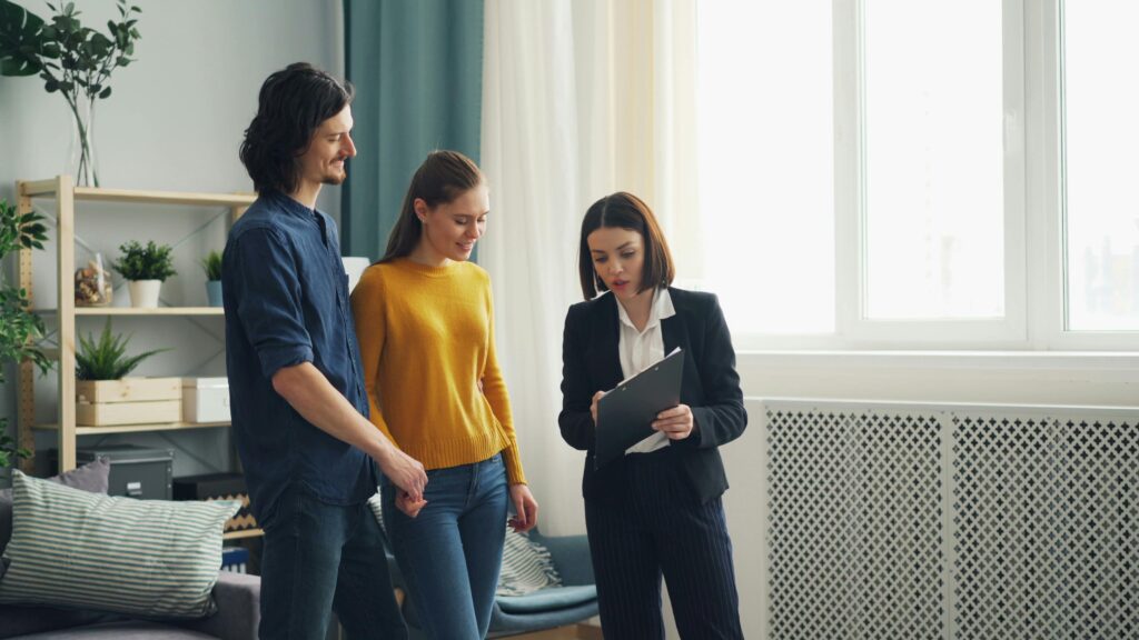 A couple standing with a property manager who's holding a clipboard.
