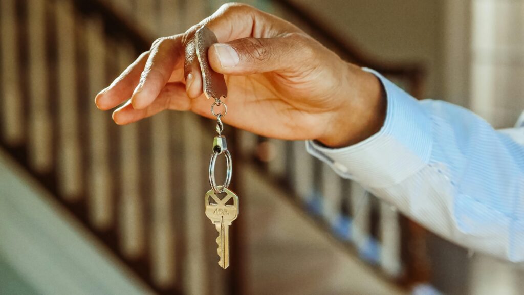 A professional holding out a house key between their finger and thumb.