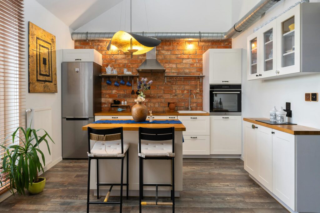 A modern, industrial-style residential kitchen with a brick feature wall.
