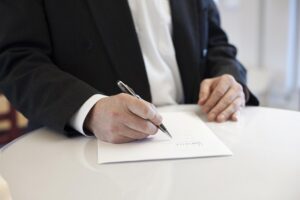Person signing a contract at a round table