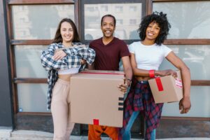 Happy tenants pose with cardboard moving boxes