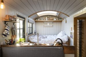 A cozy tiny home bedroom featuring a bed and a window, creating a bright and inviting atmosphere.