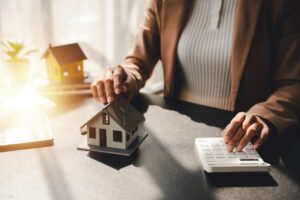Woman sitting at a desk with model home and calculator.