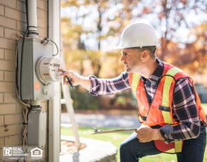 A man with hard hat standing in front of a electric panel.
