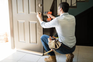 Man replacing a door lock in a house entrance.