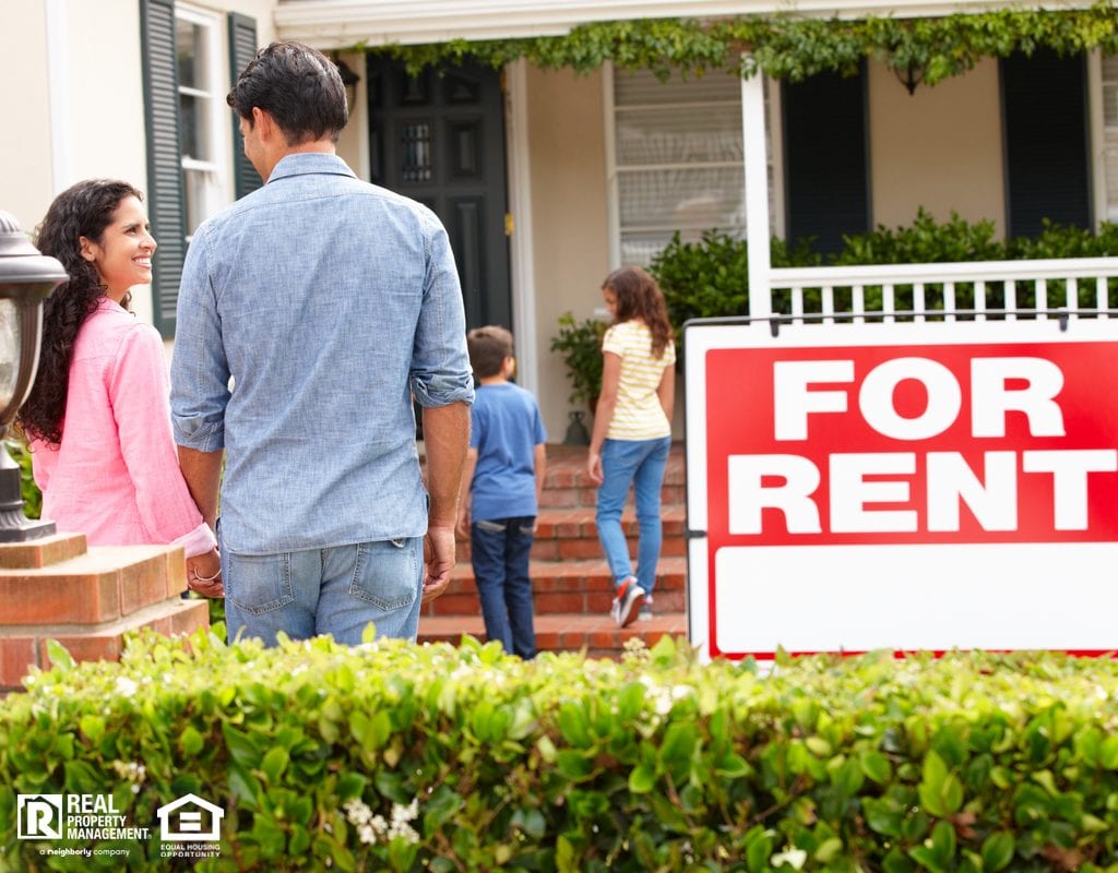 Happy Family Walking into Suburban Home with For Rent Sign in Yard