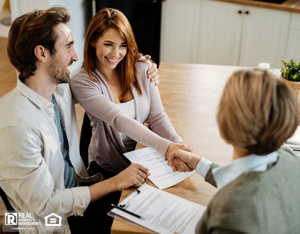 Young happy couple shaking hands with property manager while having a meeting.