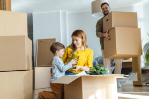 A family joyfully moving into their new home, surrounded by boxes and packing materials.