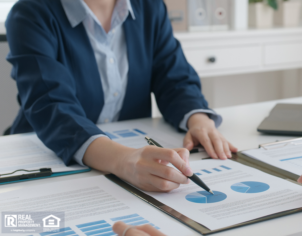 Person at a desk pointing to charts with a pen as if to explain