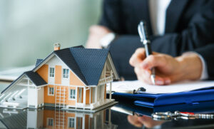 hand signing contract with a model home in the foreground