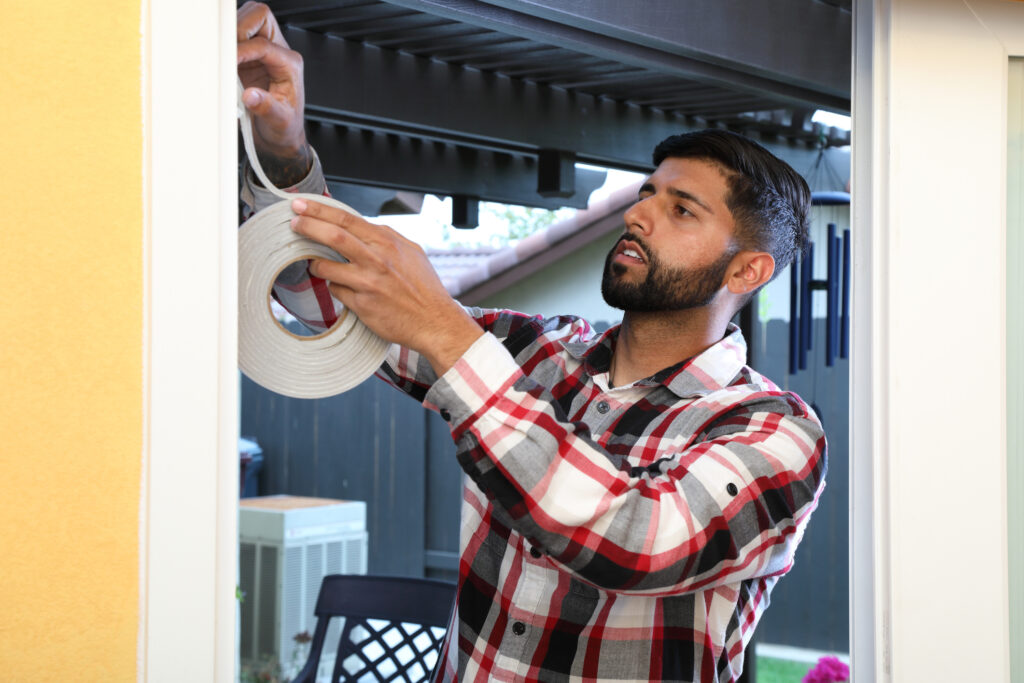Man applies weatherstripping to doorway for insulation.
