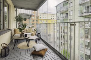A balcony decorated with comfortable chairs, plants, and lighting.