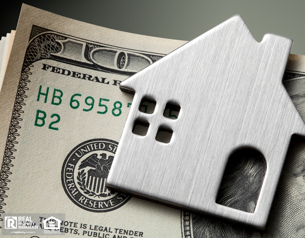 A Stack of One Hundred Dollar Bills With a Metal Model Home on Top