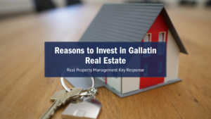 A keychain with house keys is in focus on a wooden table, next to a small model house. Overlay text reads "Reasons to Invest in Gallatin Real Estate."