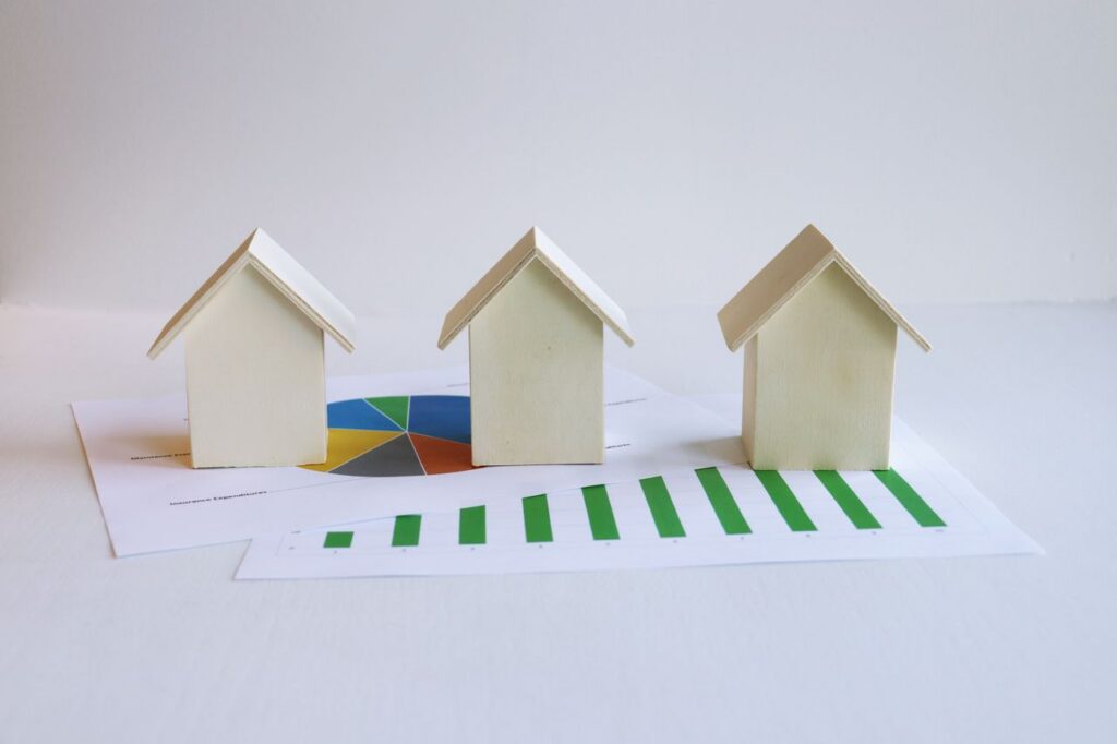 Wooden model houses on graphs depict real estate market analysis and trends