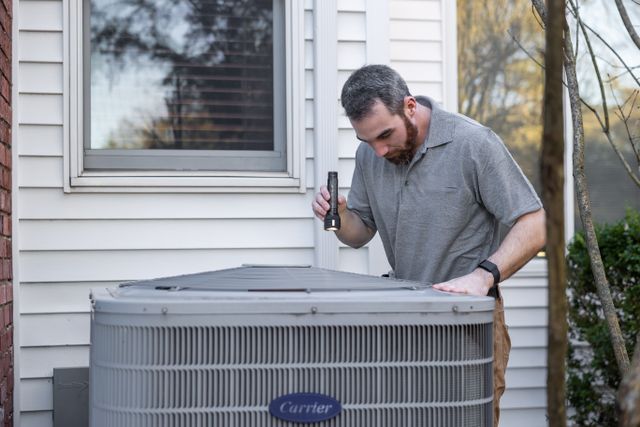 person inspecting an hvac unit outdoors