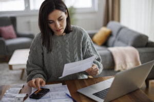 Woman checking monthly expenses and utility bills at home.