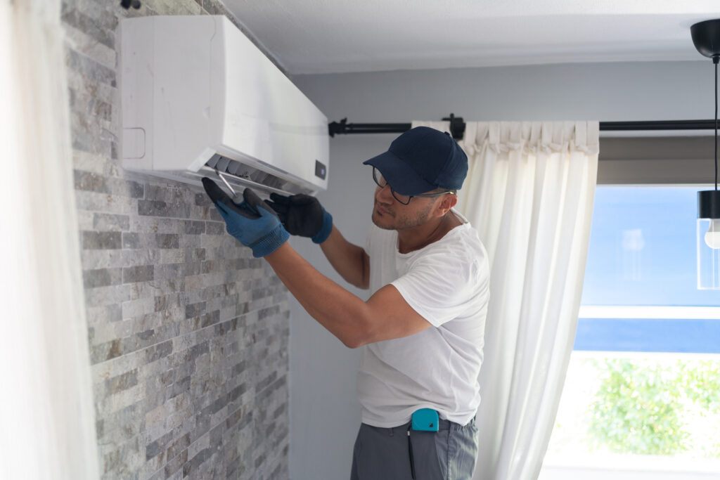 A man working on fixing an air conditioner inside a home. 