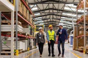 A vendor and property manager collaborate in a warehouse, surrounded by tall shelves filled with various items.