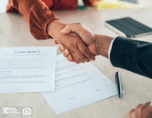 A business handshake over contracts, representing the agreement to hire a property manager.