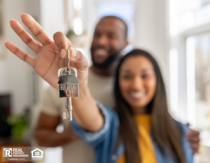 A smiling couple holds up keys to their new home.