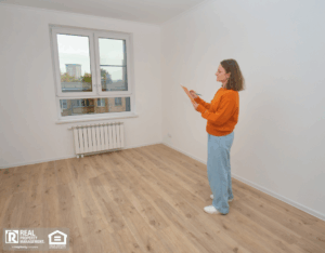 Woman inspecting empty apartment, making notes on a clipboard.