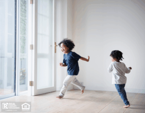 A man drafting a maintenance budget in a notebook with a pen, next to a house model on the table.