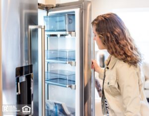 Woman looking inside modern stainless steel refrigerator.