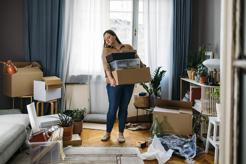 A female subletting tenant carrying boxes with personal belongings.