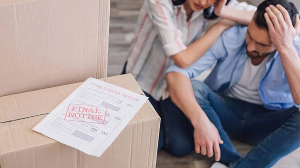 a-man-and-woman-sit-on-the-floor-looking-distressed-a-final-notice-letter-rests-on-a-stack-of-cardboard-boxes