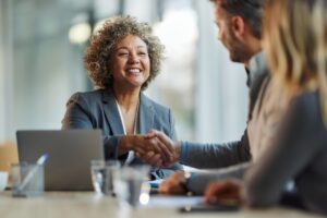 Insurance agent closing deal with real estate professionals with a handshake.